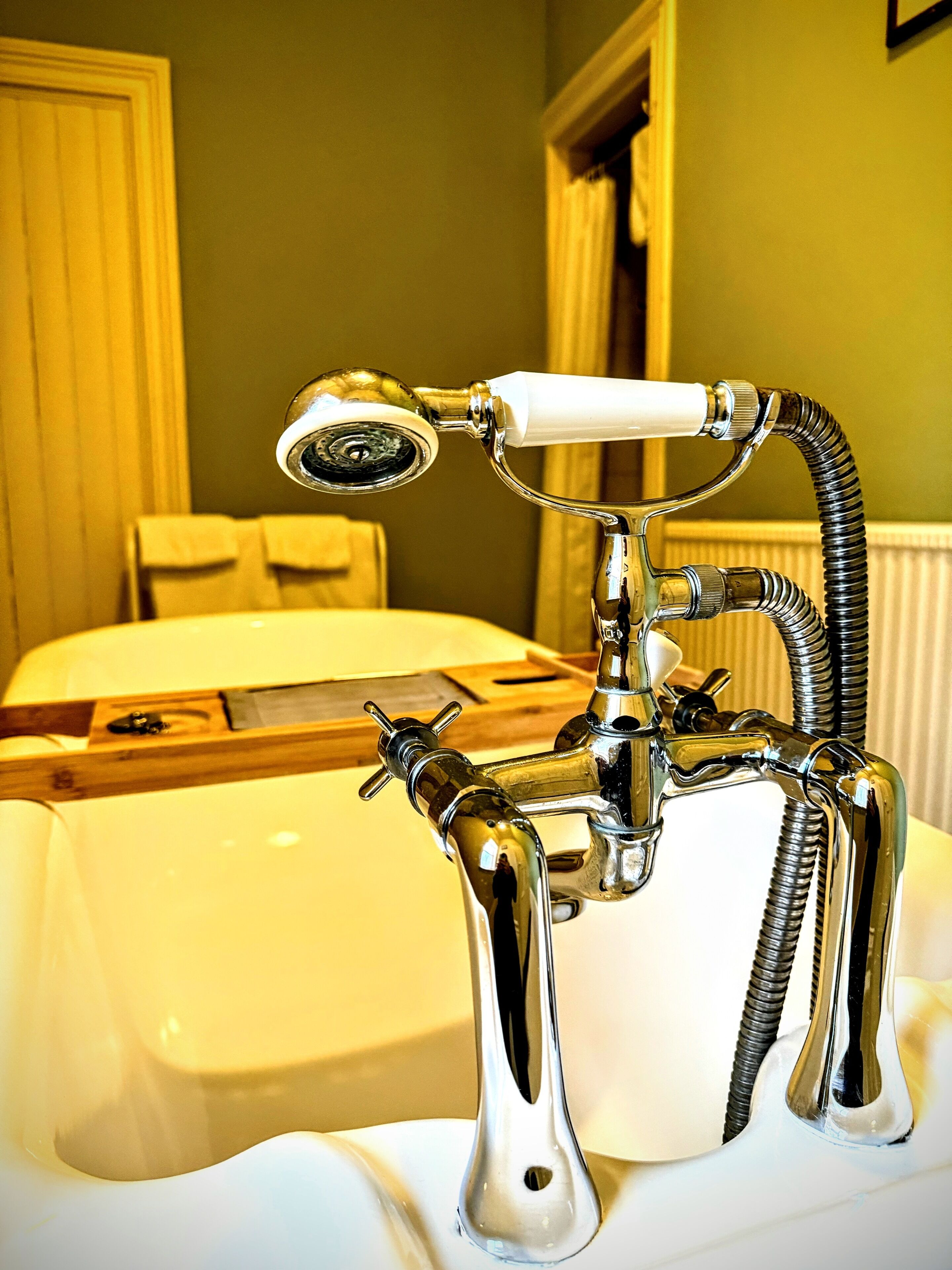 A bathroom with a white sink, chrome faucet, and a showerhead.
