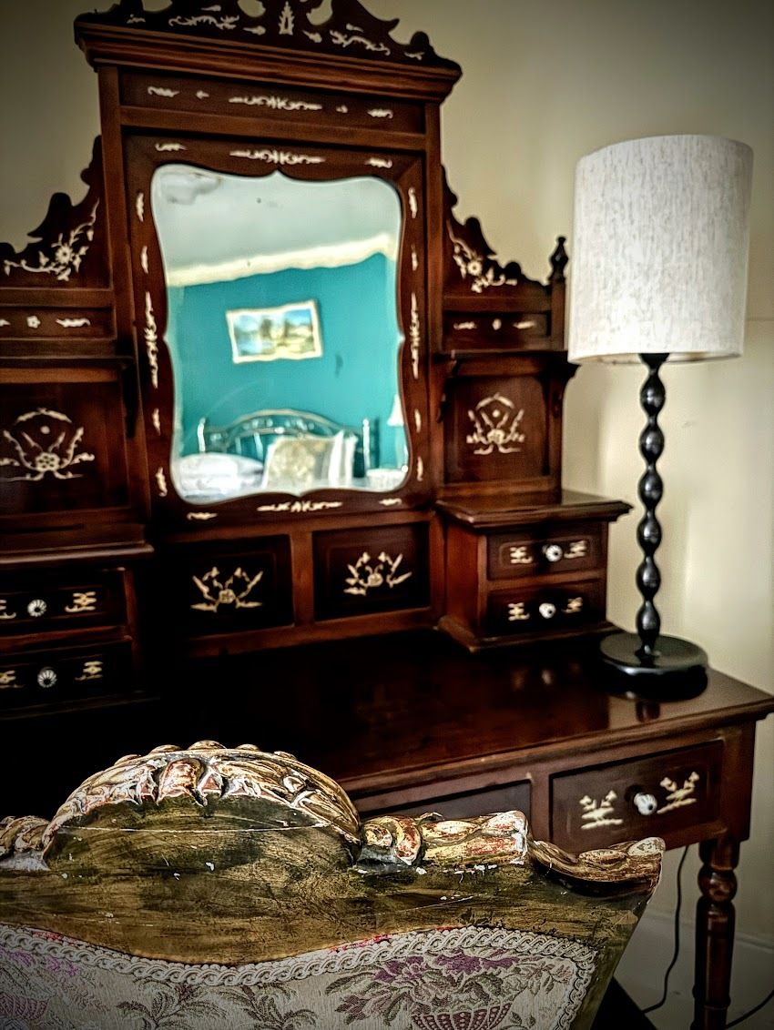 A wooden dresser with a mirror and a lamp.
