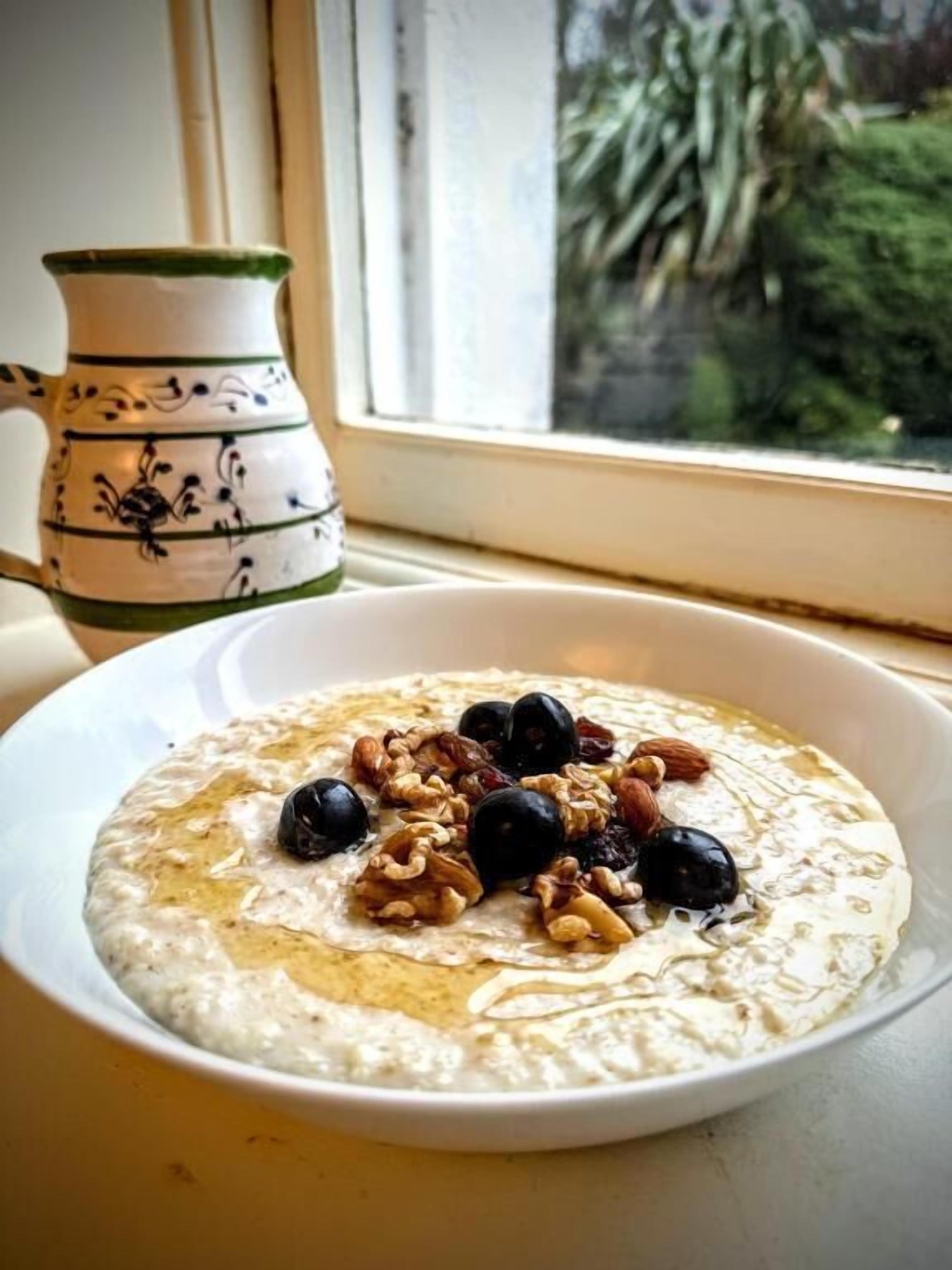 Un tazón de avena con arándanos y nueces sobre un plato blanco.