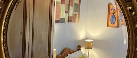 A bedroom with a bed, a nightstand, a lamp, and a wardrobe.