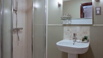 A bathroom with a glass-enclosed shower, a pedestal sink, and a mirror above it.