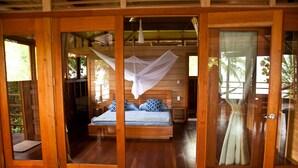 Una habitación con estructura de madera, una cama, un vidrio y vista al exterior.