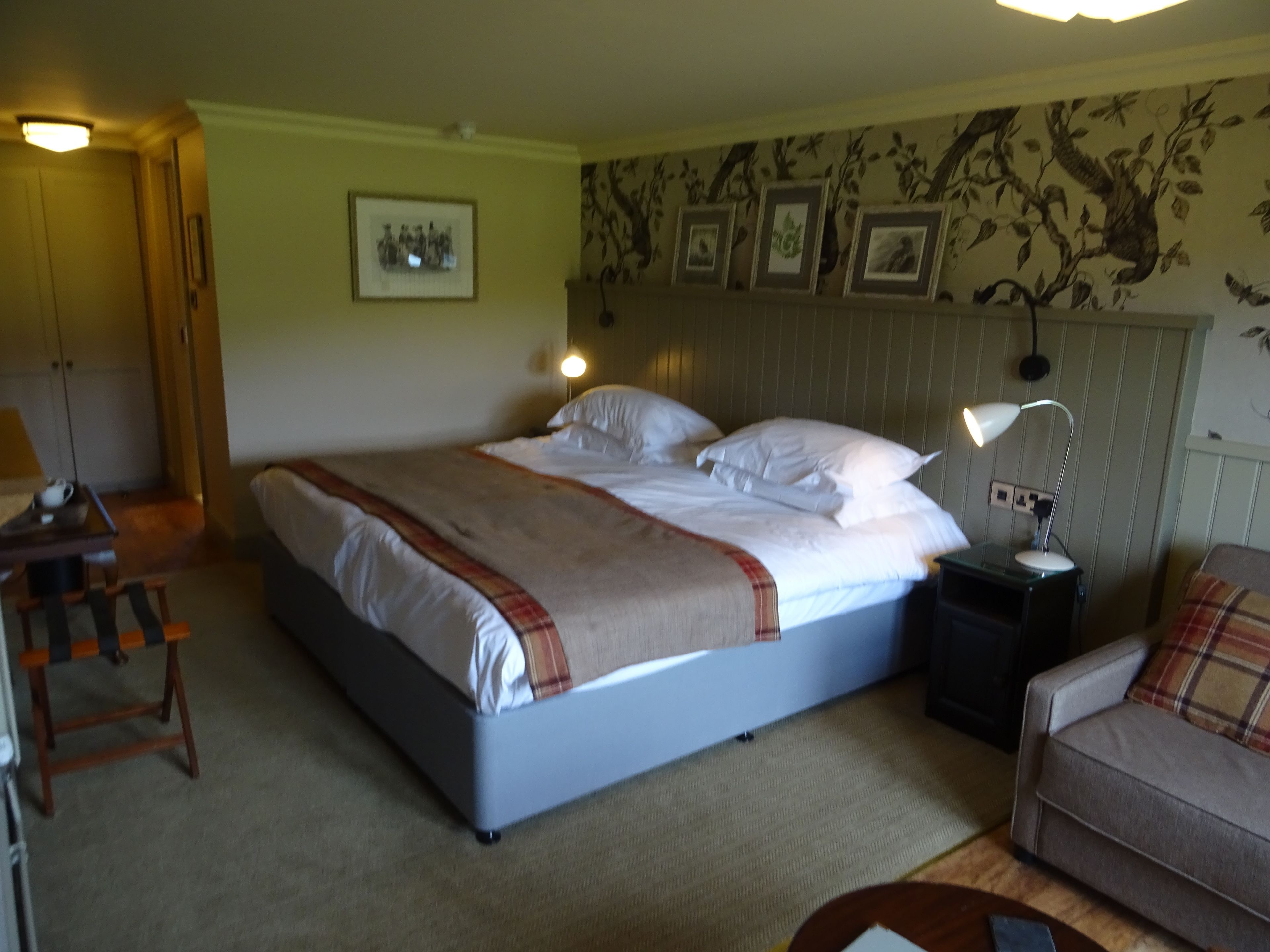 Ein Hotelzimmer mit Bett, Nachttischen, einem Sessel und einer Lampe.