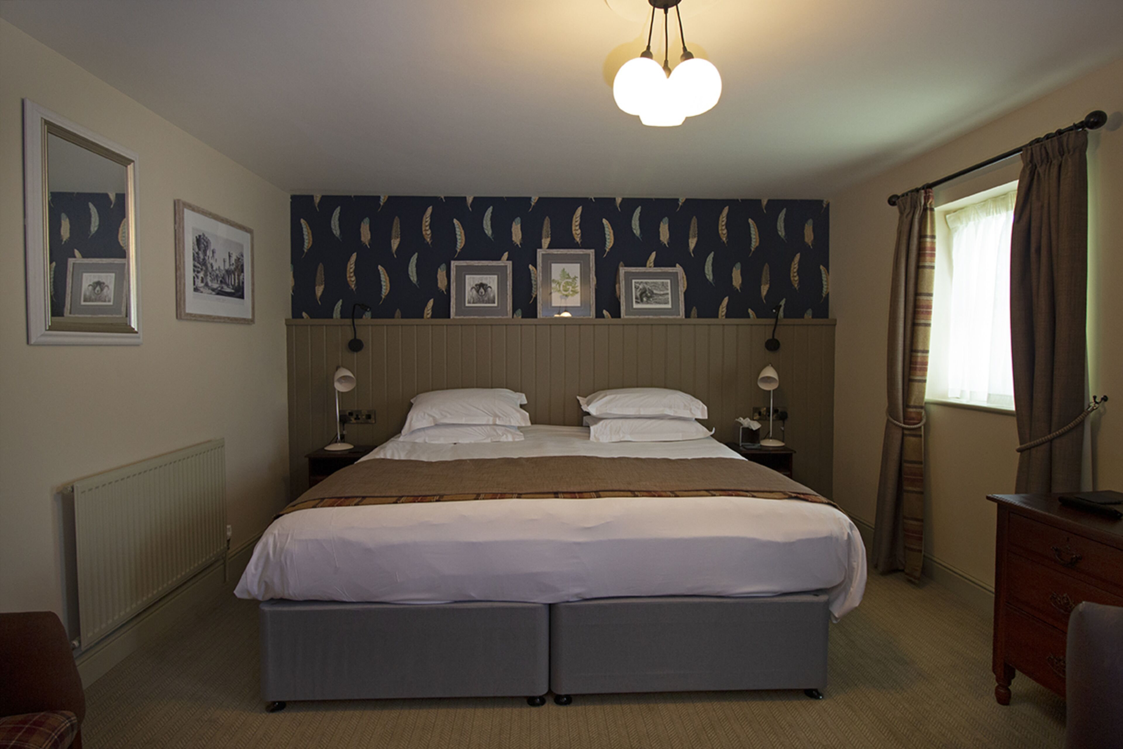 Una habitación de hotel con una cama grande, dos mesitas de noche, un aparador y una ventana con cortinas.