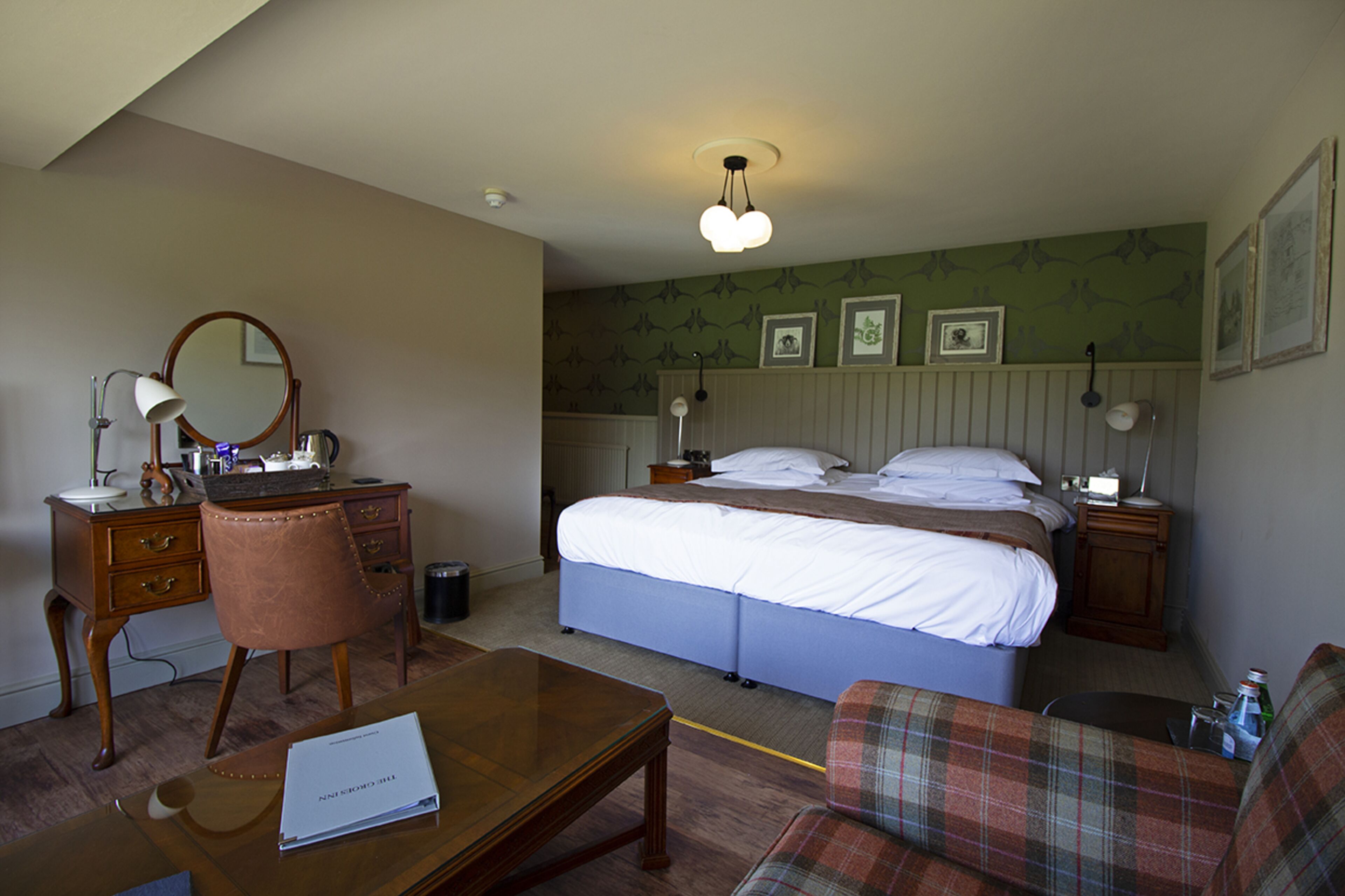 Une chambre d’hôtel avec un lit, un bureau, une chaise, une table et une lampe.