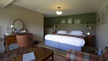 A hotel room with a bed, a desk, a chair, a table, and a lamp.
