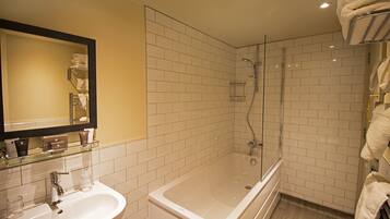 A bathroom with a bathtub, a sink, and a glass shower enclosure.