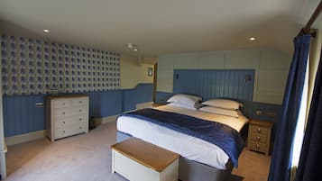 Quarto com cama, cômoda, mesa de cabeceira e um banco.