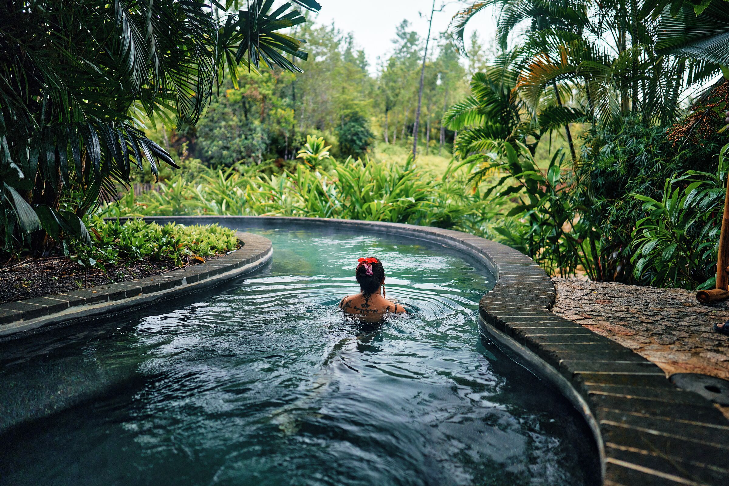 A person in a hot tub surrounded by lush greenery.