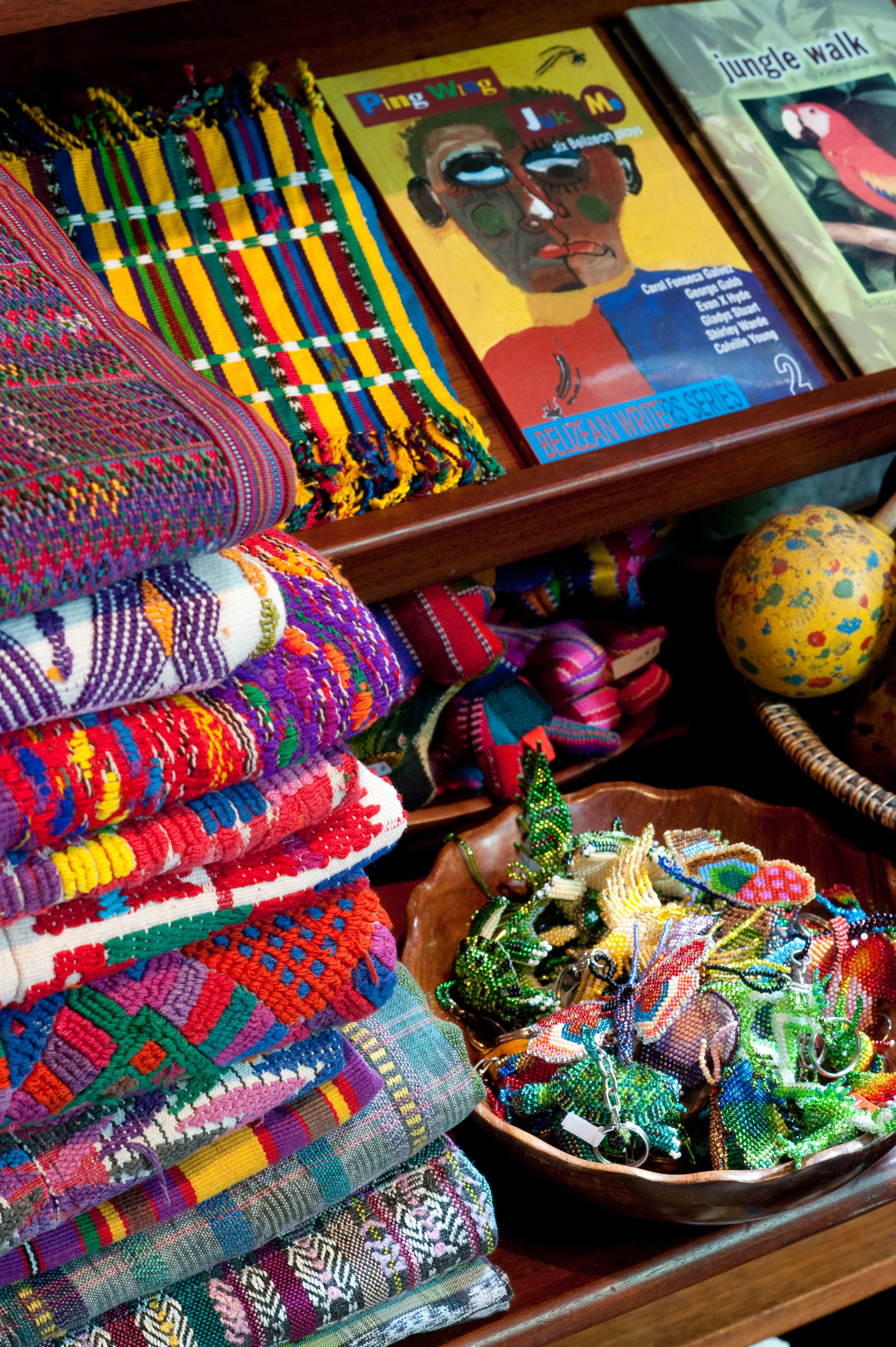 Una exhibición de textiles coloridos tejidos y un cuenco con objetos de diseños intrincados.