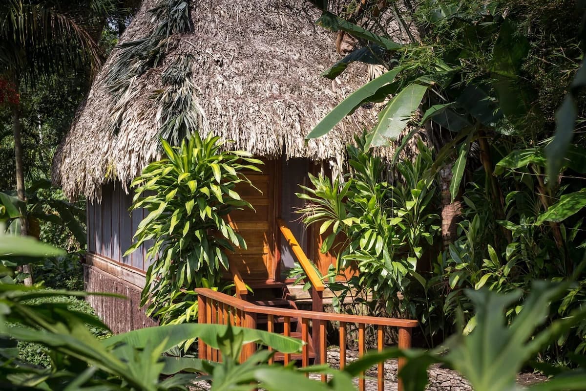Une cabane à toit de chaume, dotée d’un porche en bois et d’une balustrade en bois.
