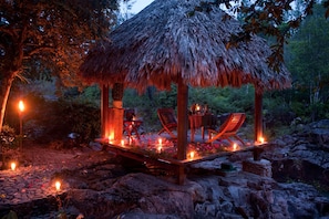 Relax in a serene outdoor setting with a thatched-roof pavilion and comfortable lounge seating.