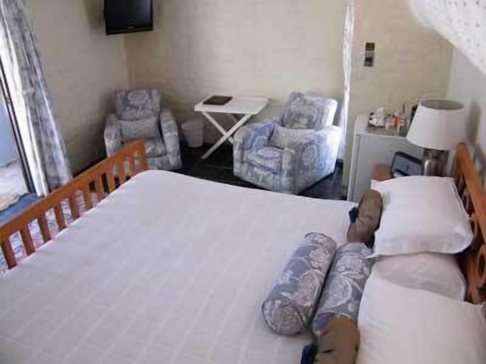 Une chambre d’hôtel avec un lit, une chaise, une petite table et une lampe.