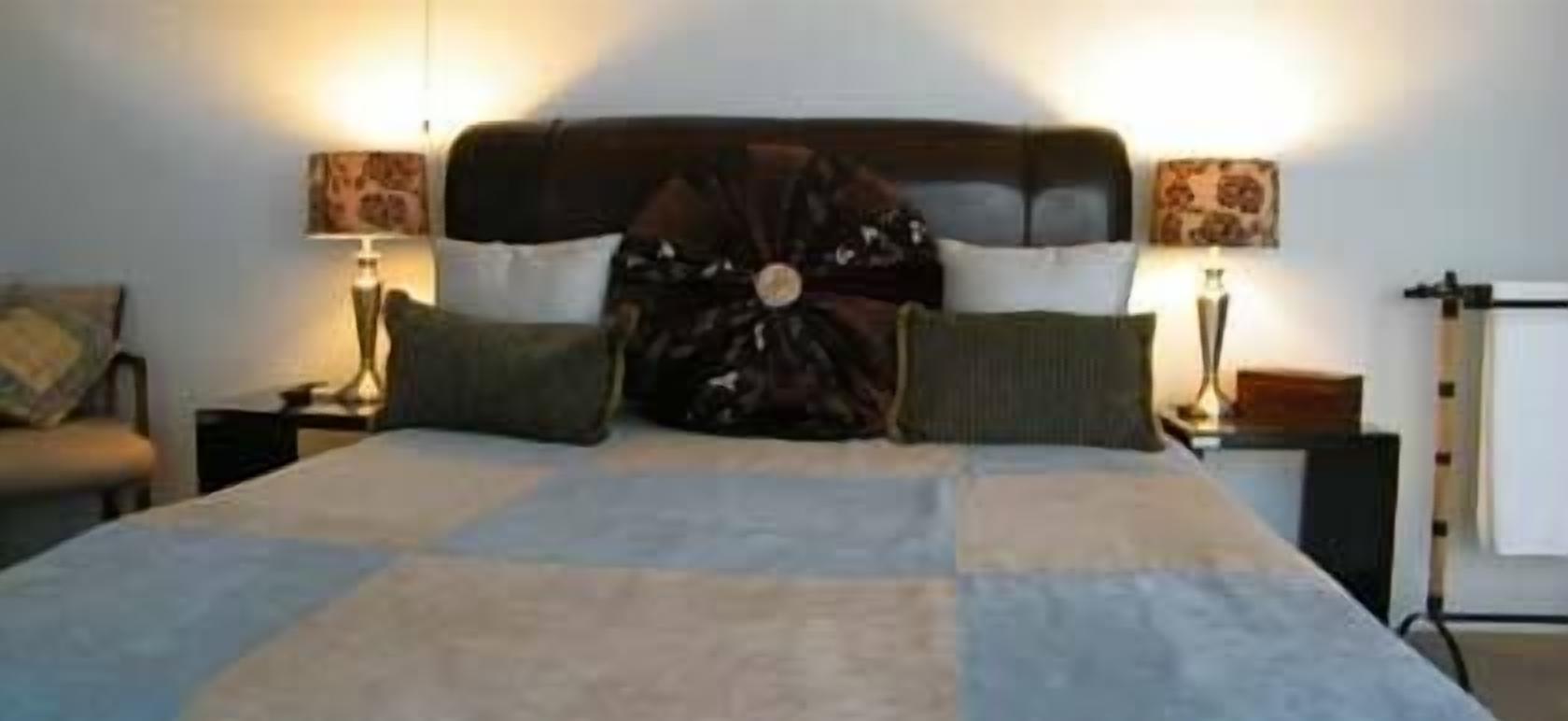 A bed with a quilt, two bedside tables, and lamps.