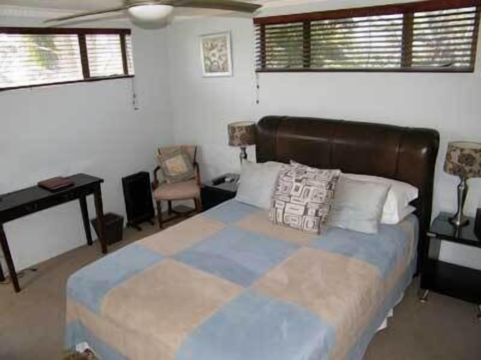 A bedroom with a bed, a chair, a desk, and a lamp.