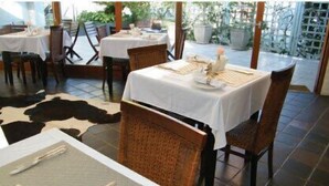 A restaurant with tables set for dining, chairs, and a cowhide rug on the floor.