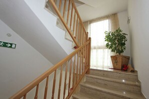 A staircase with wooden railings, a green emergency exit sign, a potted plant, and a window with curtains. - Apartment in Kaltenbach near Ski Lift (Stumm)