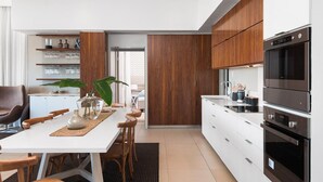 Uma cozinha moderna com armários brancos, detalhes em madeira e eletrodomésticos de aço inoxidável.