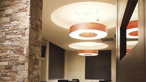 A modern hotel lobby with stone walls, a wooden reception desk, and a seating area with chairs and tables. - Hotel Mar de Plata (Sarria)