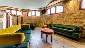A room with a stone wall, wooden floor, and green and yellow sofas. - Hotel Mediterraneo (Guardamar del Segura)