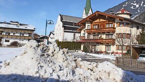 A hotel with a traditional Alpine architectural style, featuring a prominent church steeple and a large snow-covered courtyard. - Apartment in Kaltenbach near Ski Lift (Stumm)