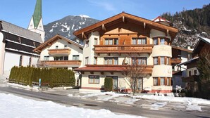 A multi-story hotel with a traditional Alpine architectural style, featuring wooden balconies and a mountain backdrop. - Apartment in Kaltenbach near Ski Lift (Stumm)
