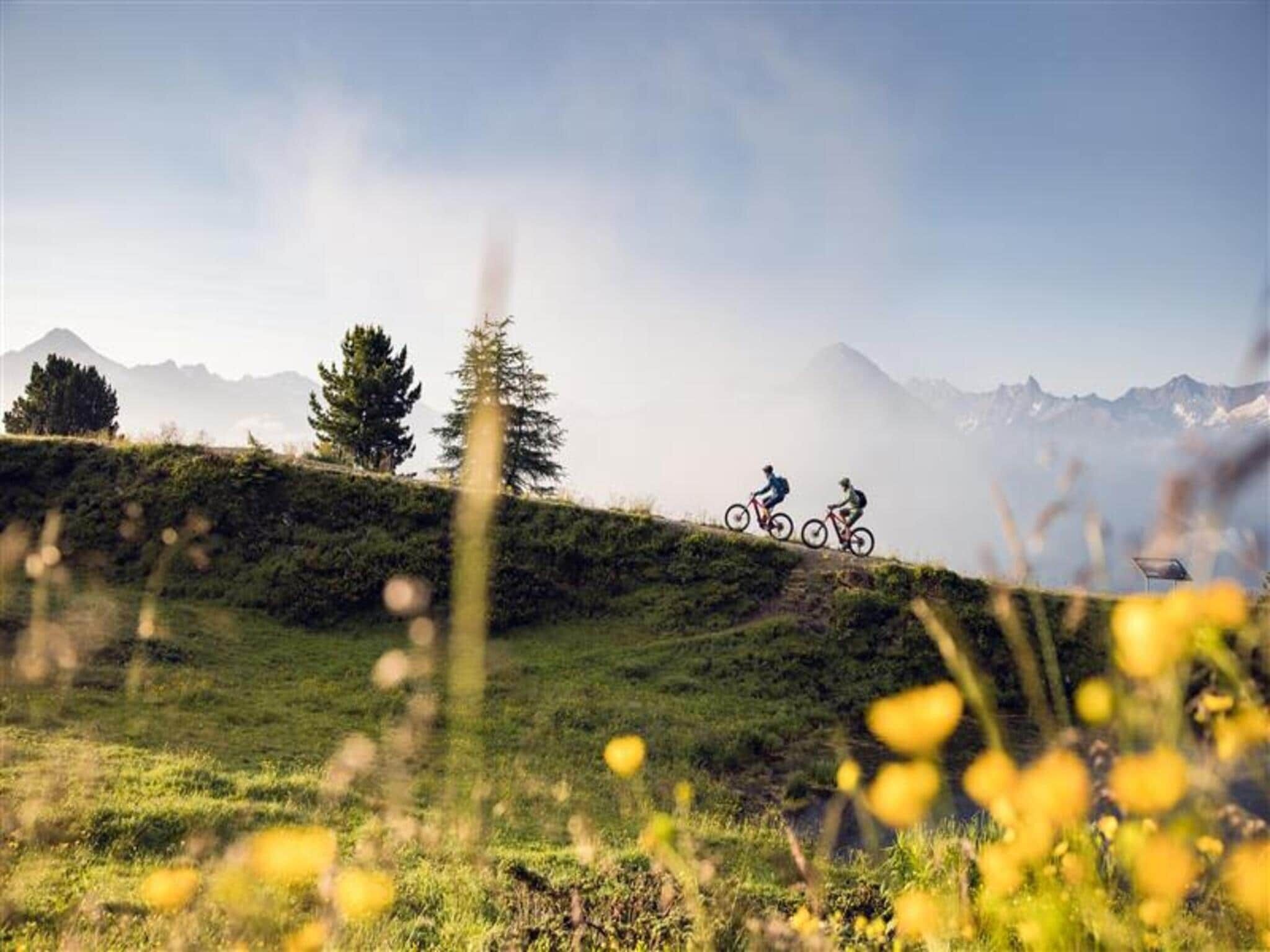 A mountain landscape with cyclists on a trail.