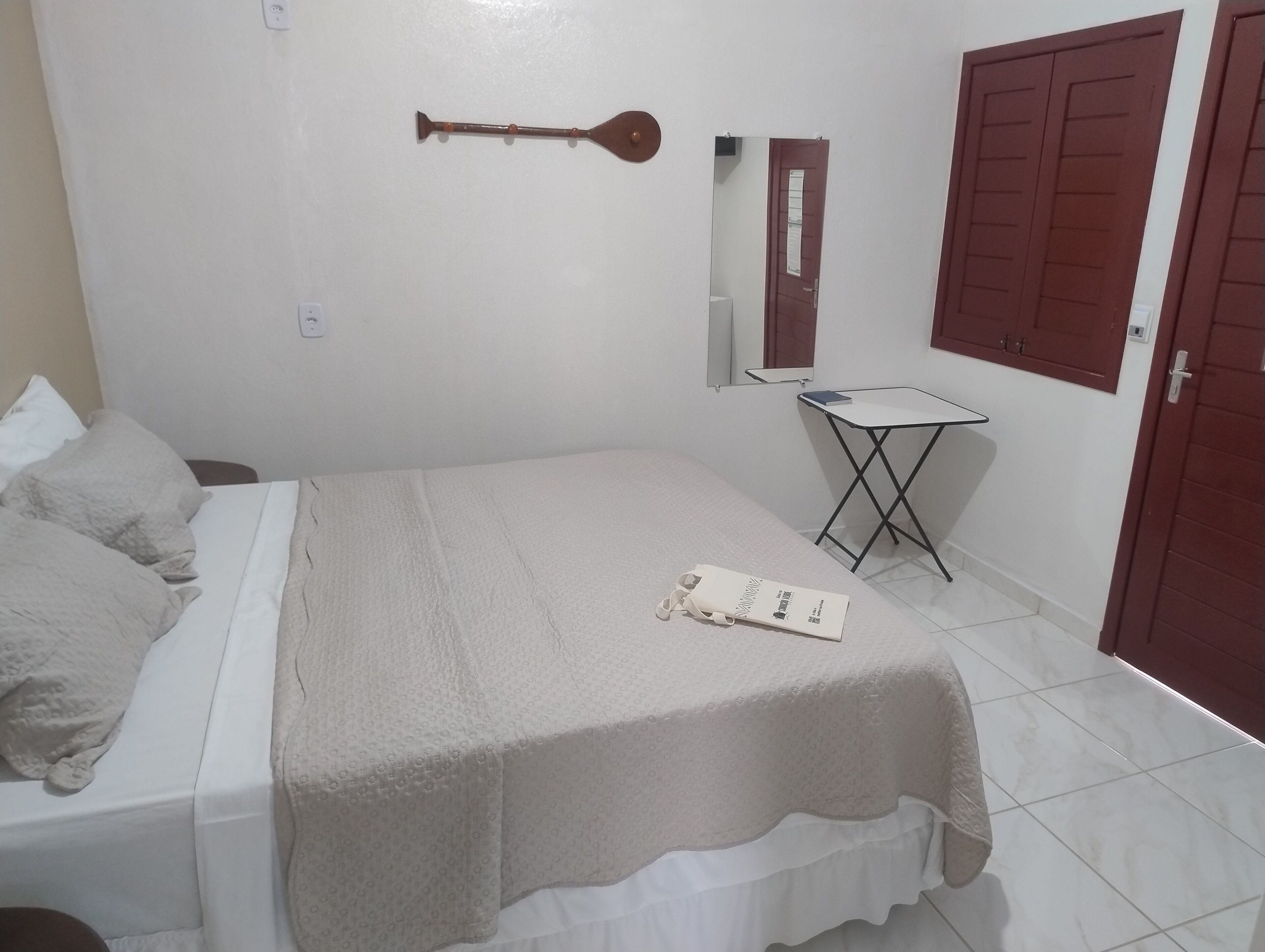 Un dormitorio con cama, una mesita, un espejo y un armario.