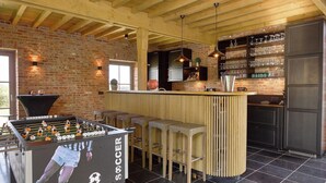 Een gezellige bar met een tafelvoetbalspel, barkrukken en een bakstenen muur.