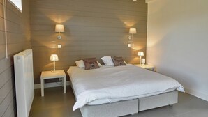 Een slaapkamer met een groot bed, twee nachtkastjes en wandlampen.
