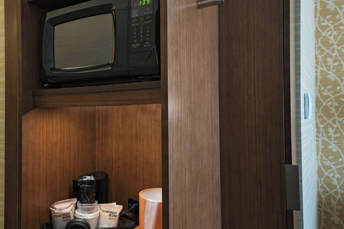 A kitchen area with a microwave, coffee maker, and storage containers.