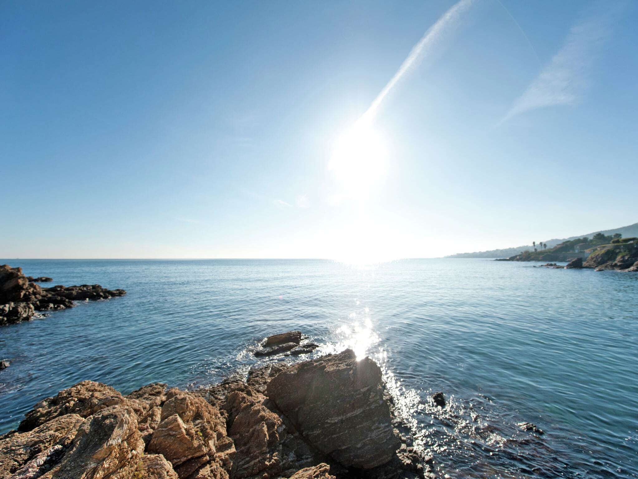 A coastal scene with rocky outcrops and calm sea under a clear sky.