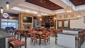 A spacious restaurant with high ceilings, exposed beams, and a variety of seating options including tables and booths. - Four Points by Sheraton Houston Intercontinental Airport (Houston)