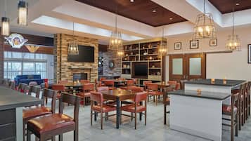 A restaurant interior with a bar area, seating, a fireplace, and a television.