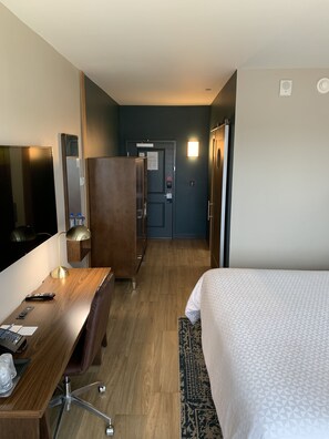 Una camera d'albergo con un letto, una scrivania, una sedia e un armadio.