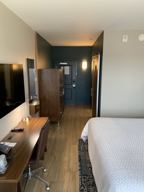 A hotel room with a bed, desk, chair, and a wardrobe.