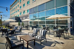 An outdoor patio area with tables and chairs, umbrellas, and string lights. - Four Points by Sheraton Houston Intercontinental Airport (Houston)