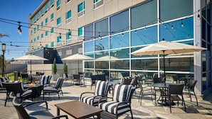 An outdoor patio area with seating, tables, and umbrellas. - Four Points by Sheraton Houston Intercontinental Airport (Houston)
