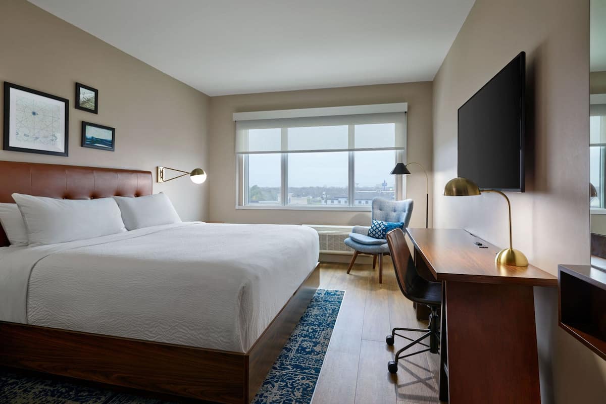Hotelkamer met een groot bed, een bureau met stoel, een televisie en een raam met uitzicht over de stad.