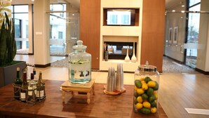 A reception area with a wooden reception desk, a fish tank, a fireplace, and a large window. - Hilton Garden Inn Austin Airport (Austin)