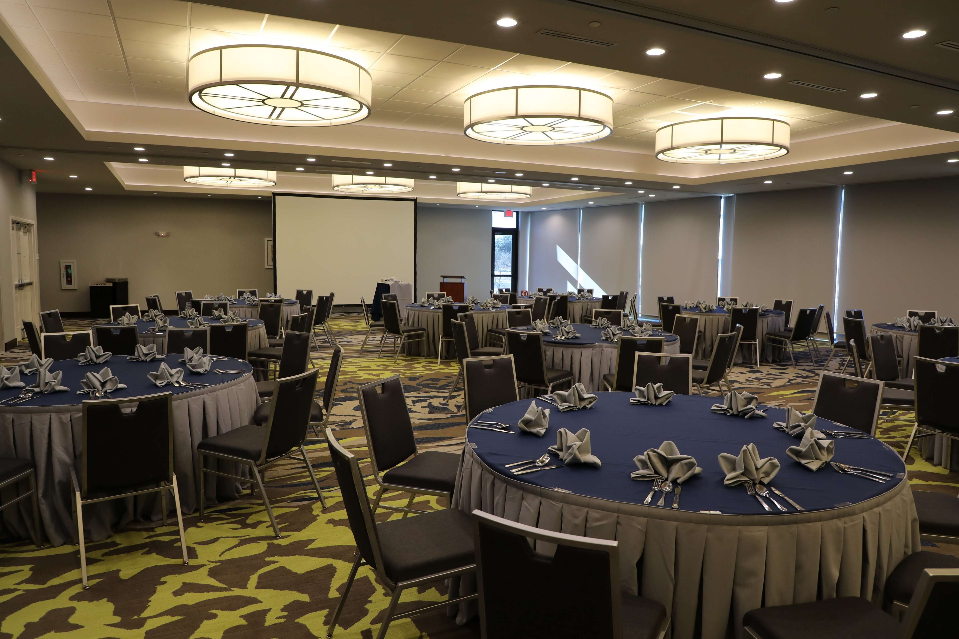 A conference room with multiple round tables, each set with chairs and table settings.
