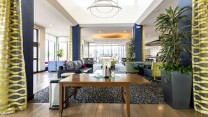 A spacious lobby with a wooden reception desk, seating area, and large windows. - Hilton Garden Inn Austin Airport (Austin)