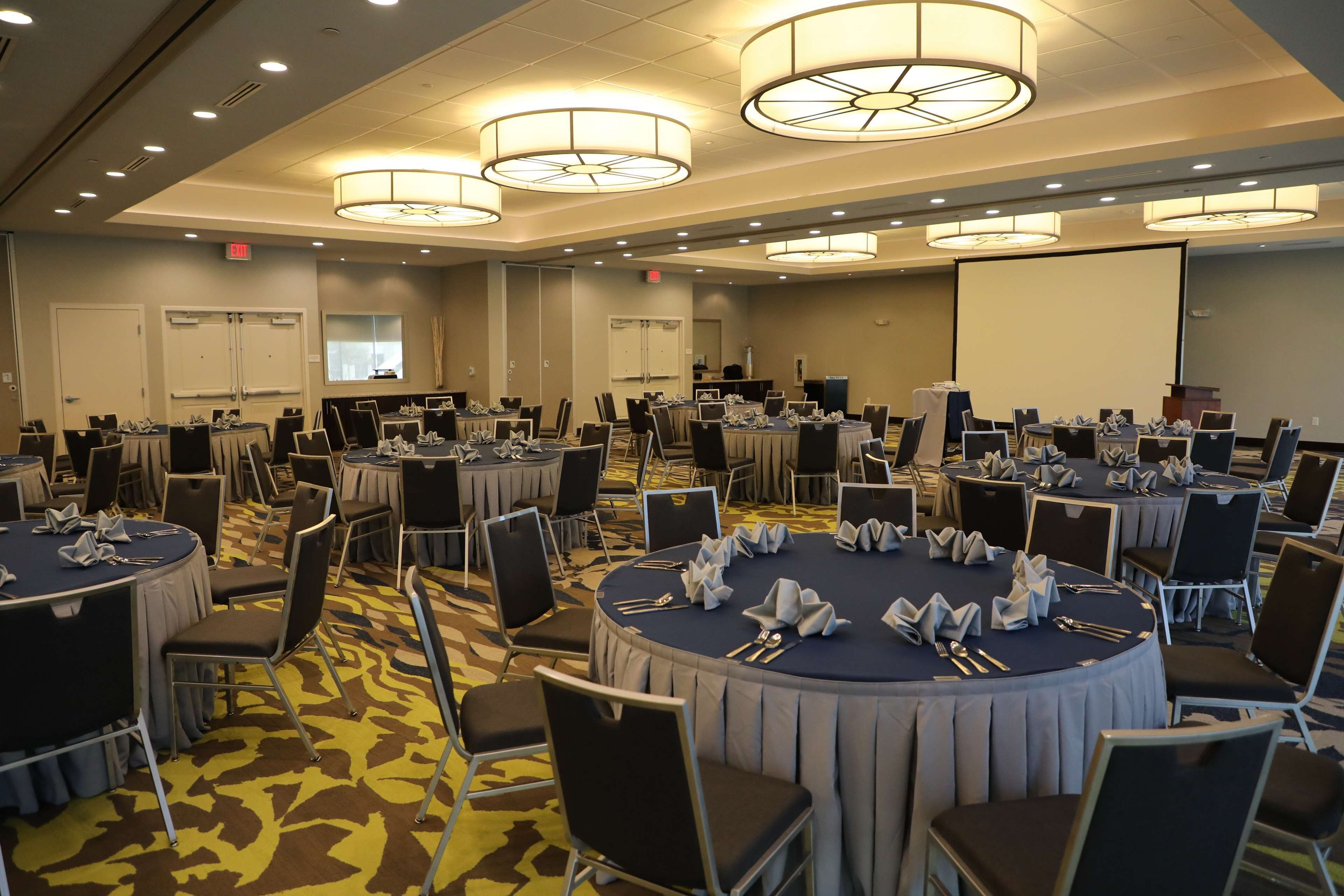 A conference room with multiple round tables, each set with chairs and table settings.