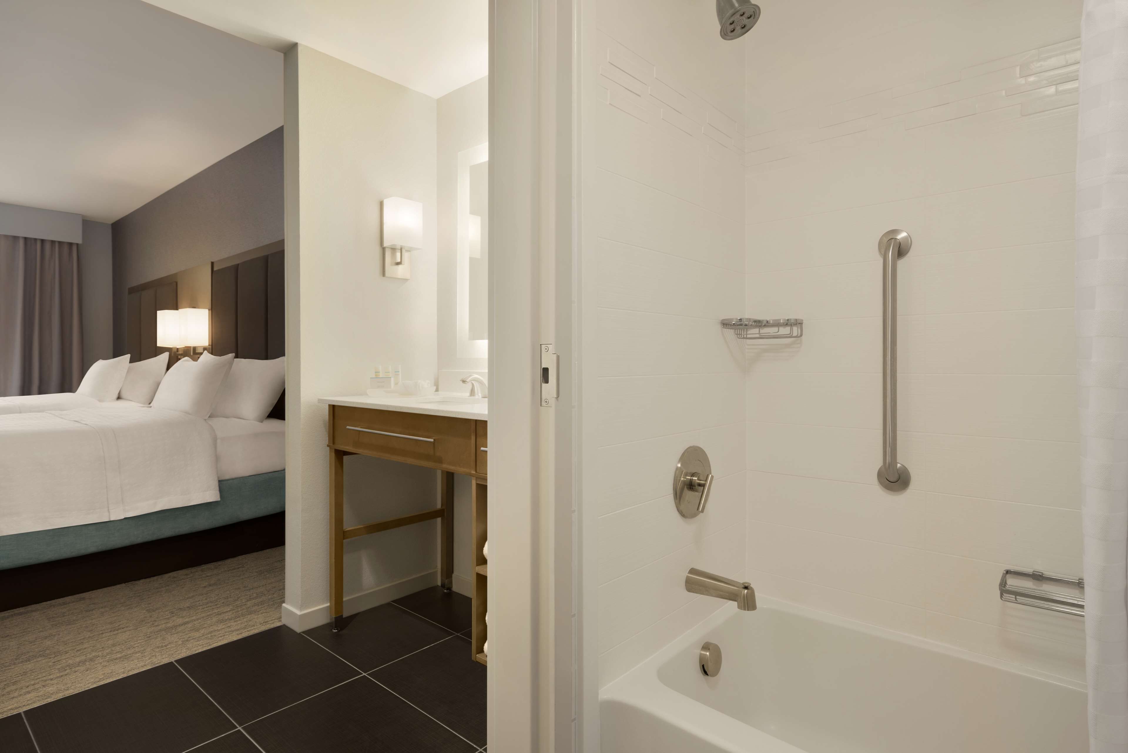A hotel room with a bed, a desk, a bathroom with a bathtub and shower.