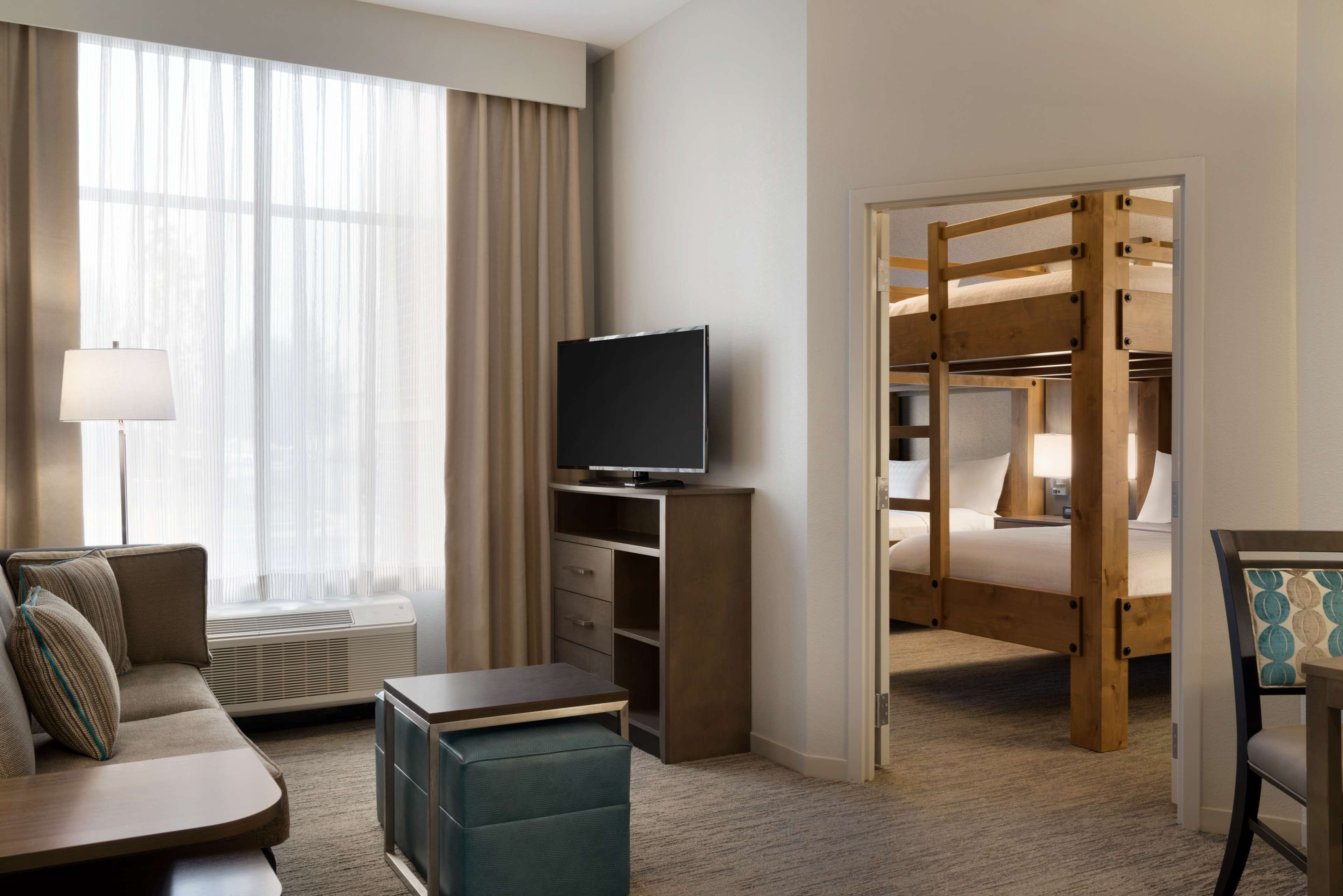 Een hotelkamer met een bank, televisie en stapelbedden.