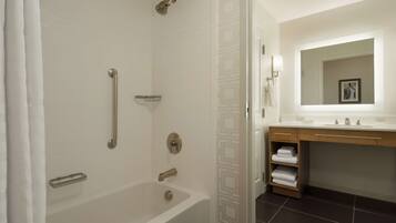 A modern bathroom with a bathtub, a shower with a handheld showerhead, a towel rack, and a vanity with a mirror and sink.