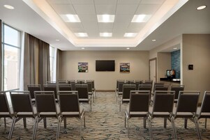 A conference room with rows of chairs, a large flat-screen TV, and artwork on the walls.