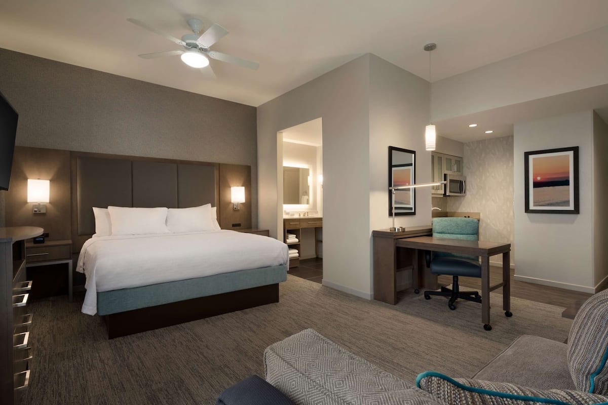 Une chambre d’hôtel équipée d’un lit, d’un bureau, d’une chaise et d’un ventilateur de plafond.