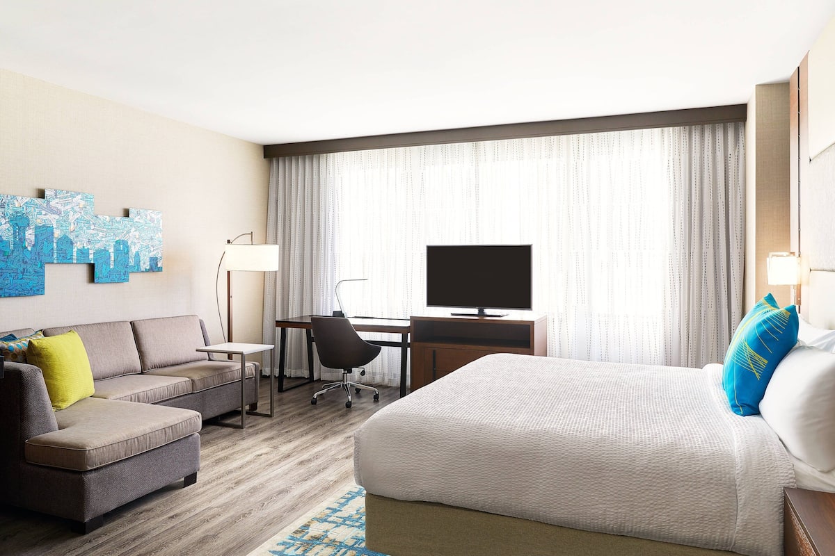 Une chambre d’hôtel comprenant un lit, un canapé, un bureau, une chaise et un téléviseur.