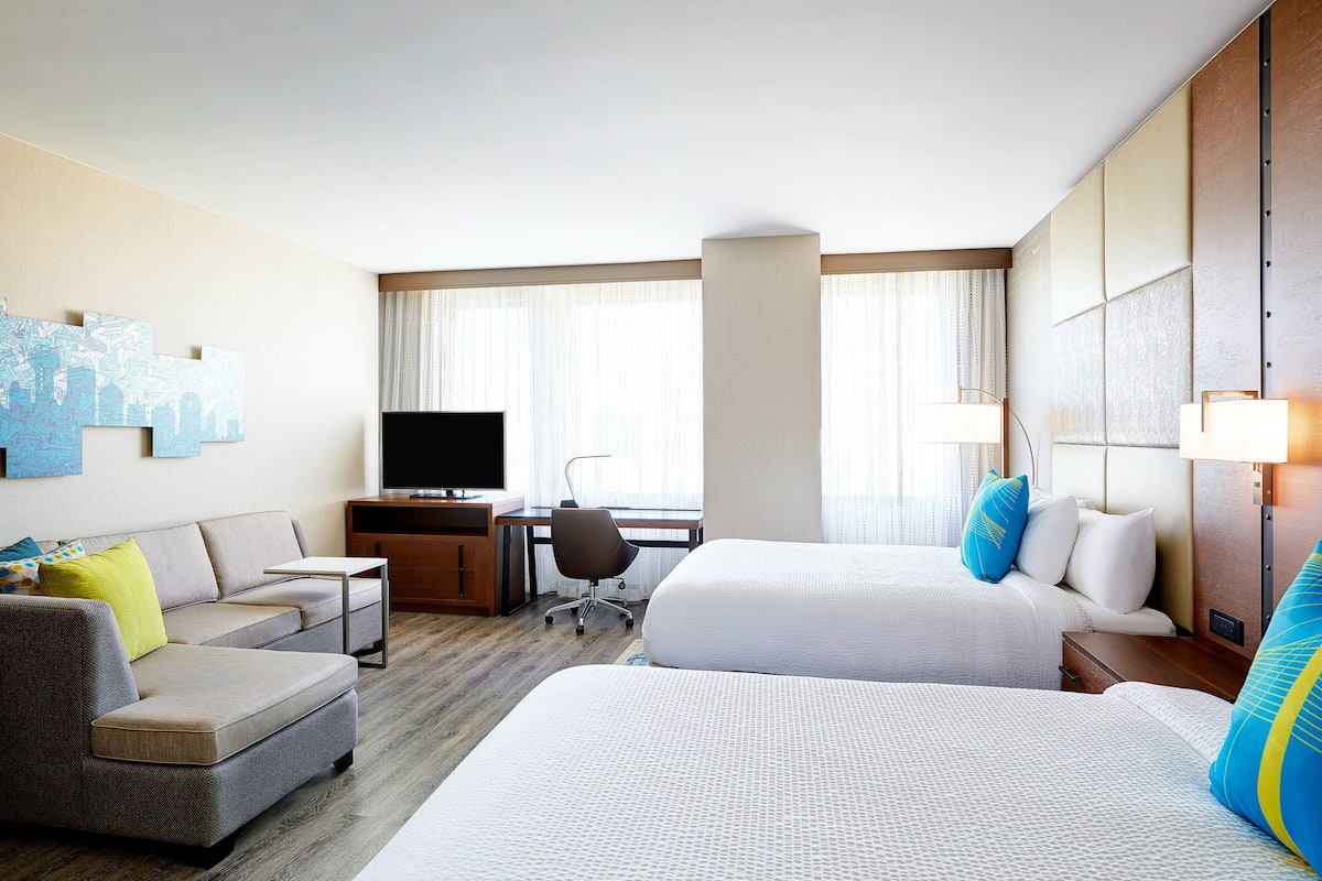 Une chambre d’hôtel avec deux lits, un canapé, un bureau et une télévision.